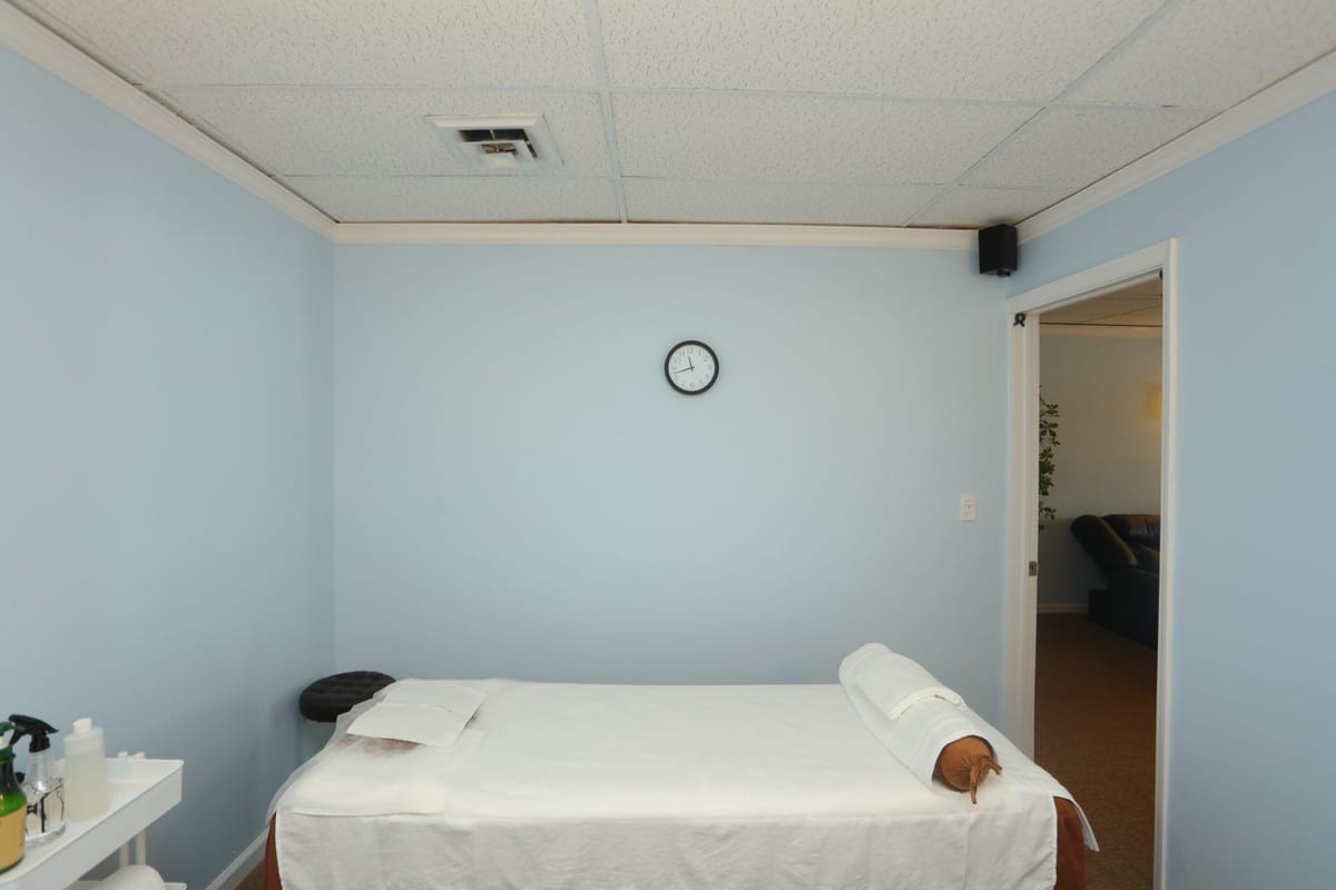 A quiet treatment room with soft blue walls and fresh linens at Paradise Massage in Matawan, NJ.